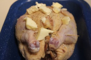 Secure legs with a skewer and dot with butter