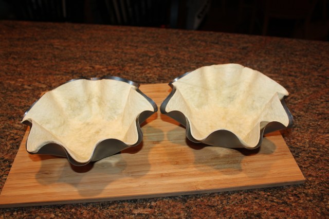 Press tortilla shells into pans